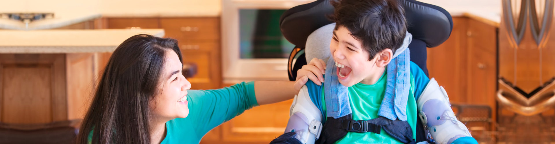 disabled boy in wheelchair laughing with his caregiver