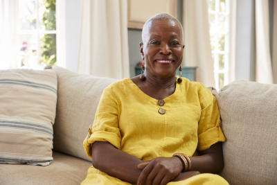 Portrait Of Smiling Senior Woman Sitting On Sofa At Home